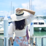 excited tourist in white hat enjoying and standing on the dock with luxury yachts during summer