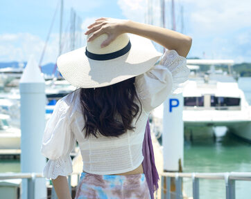 excited tourist in white hat enjoying and standing on the dock with luxury yachts during summer